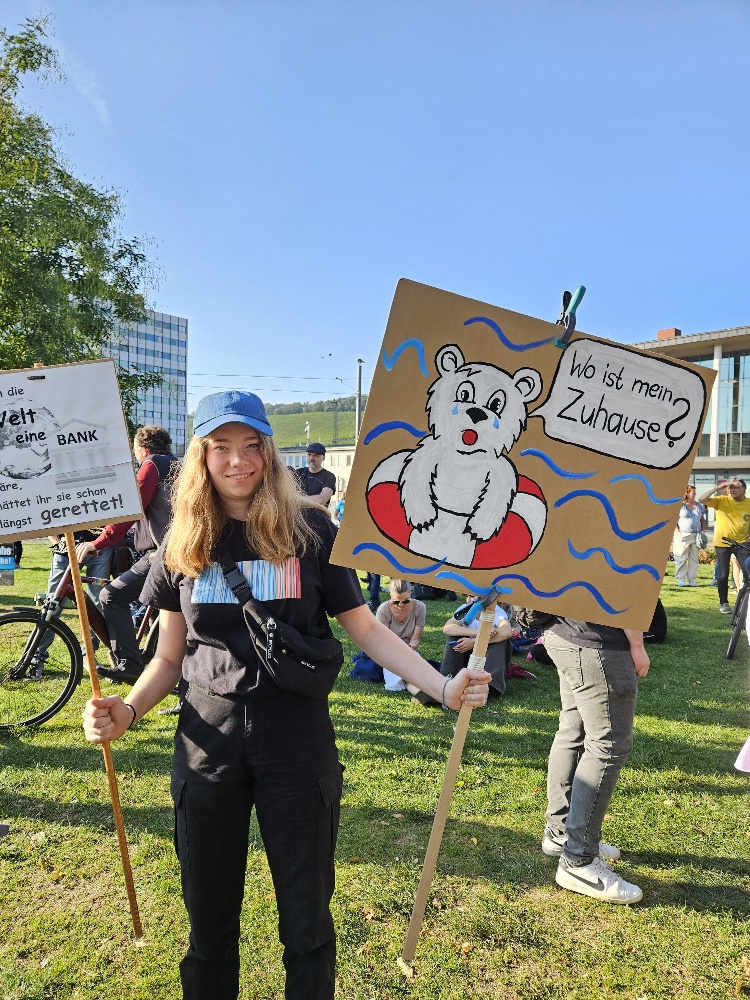 Demo-Teilnehmerin mit Demonstrationsschild: ein Eisbär mit einer Sprechblase darüber: "Wo ist mein Zuhause" 