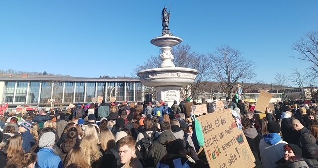 Ein Bild von der Demo gegen Rechts am 01.02. Man sieht eine Menschenmenge vor dem Würzburger Hauptbahnhof. In der Mitte ist ein Brunnen zu sehen