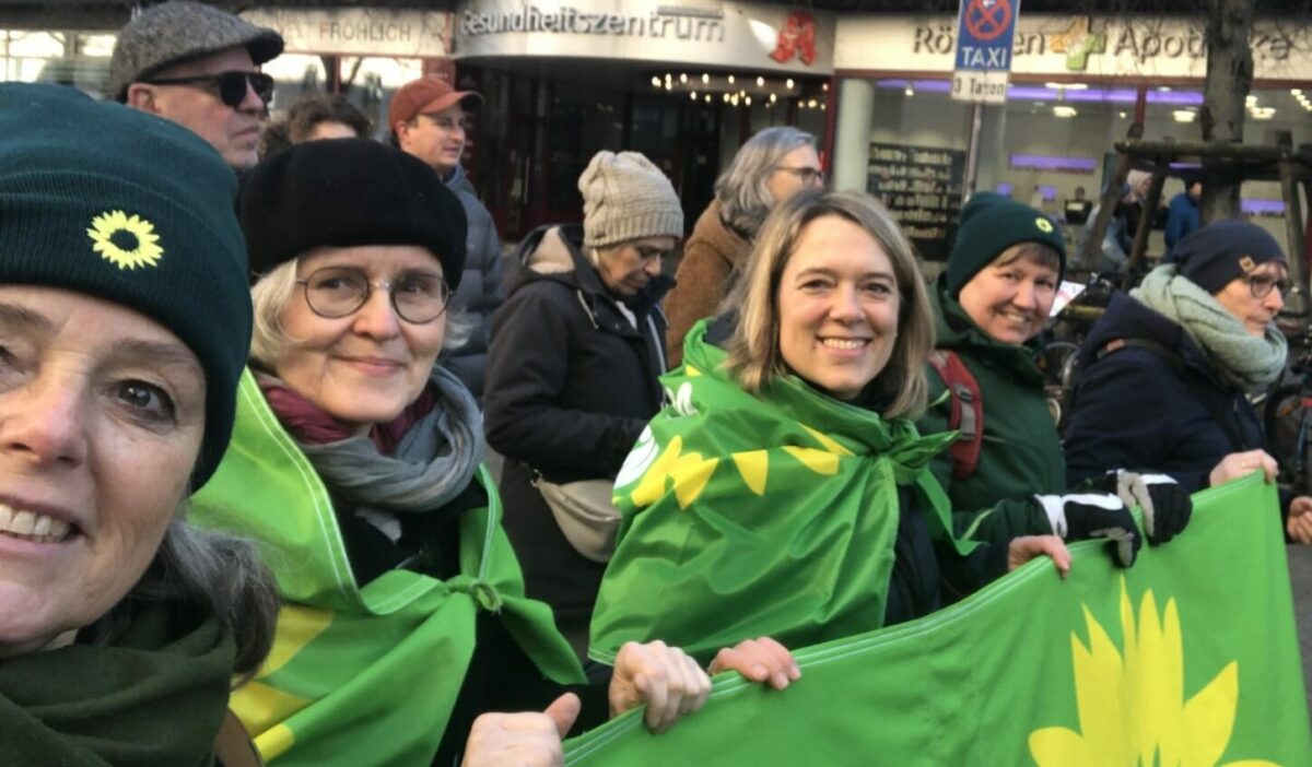 Die Grünen bei der Demo gegen Rechts. Auf dem Foto sind vier Menschen von den Grünen zu sehen. Die drei halten ein grünes Banner, zwei tragen grüne Flaggen