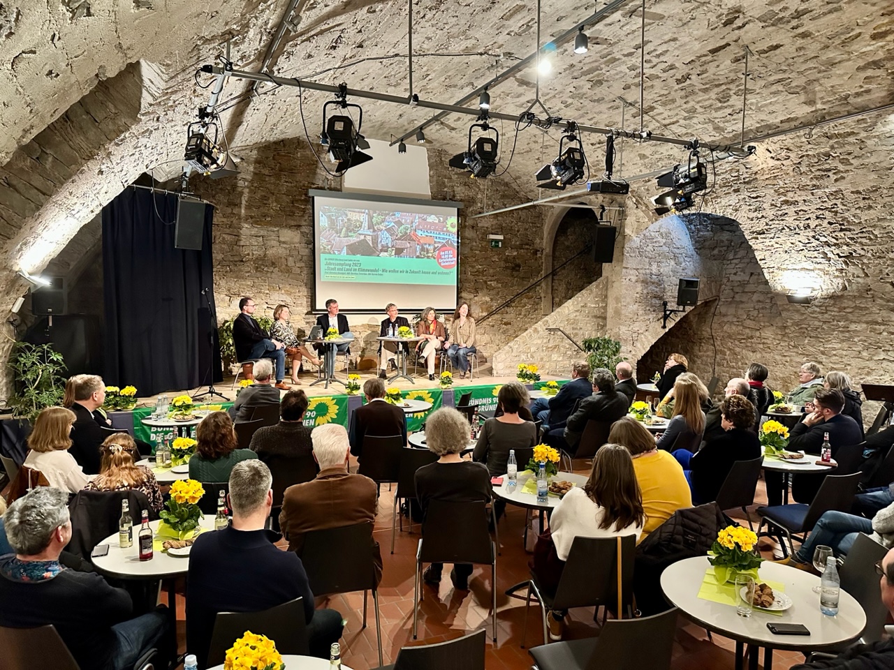 Blick in den Gewölbekeller mit Gästen an Tischen und dem Podium im Hintergrund